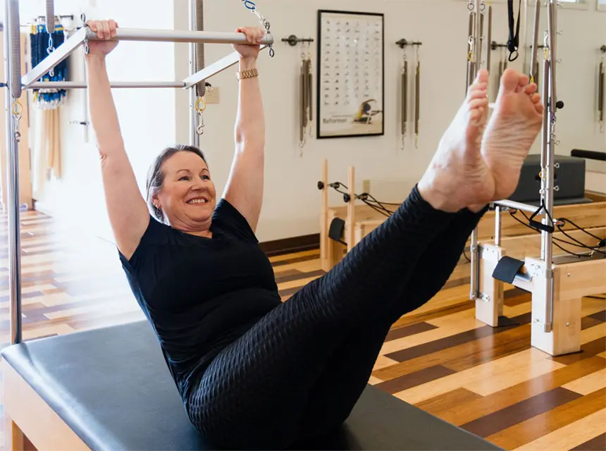 private-pilates-session Middle-aged woman performing a teaser exercise on the Cadillac during a private Pilates session